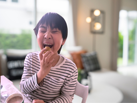 玄米粉で作られたグルテンフリーマドレーヌを笑顔で食べる子供の様子。安心素材で家族みんなが楽しめる、シアイーツのやさしいスイーツ。